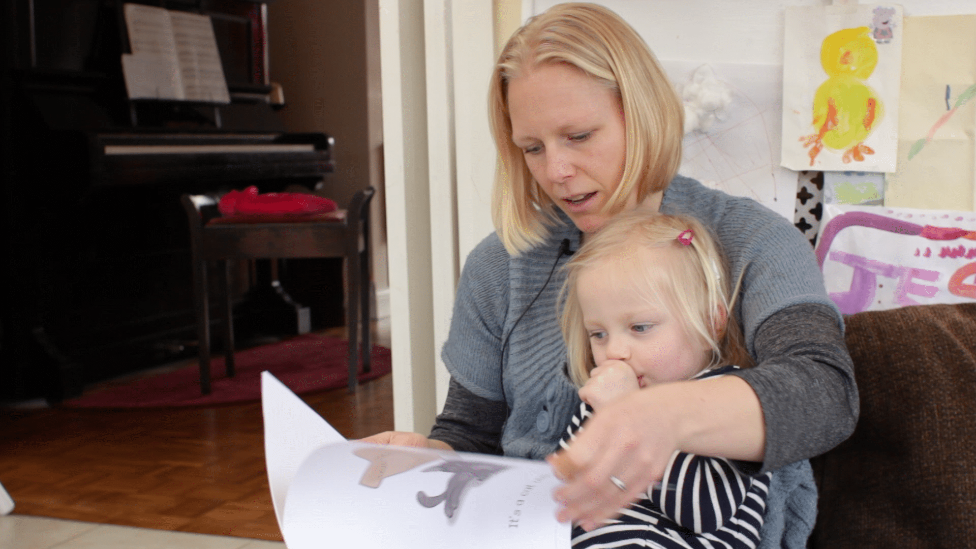 a mother uses acoustic highlighting while pointing at pictures on a paper when talking to her very young daughter