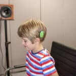 A young boy sits in a sound studio to take a