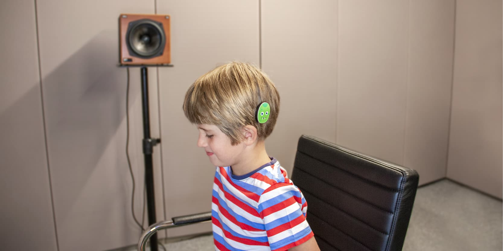 A young boy sits in a sound studio to take a
