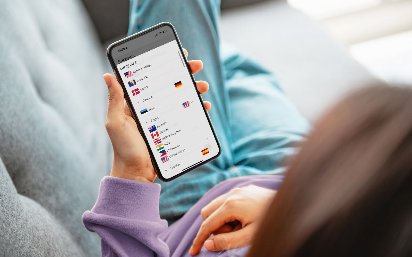 A ReDi app user relaxes on the sofa at home and notices that the app supports auditory and speech rehabilitation support in over 155 languages.