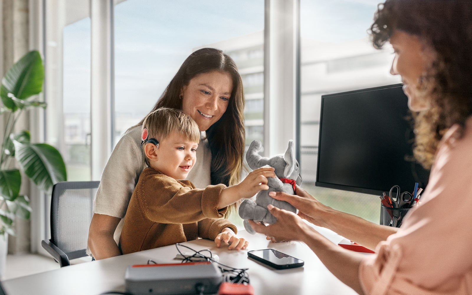 An audiologist works with a small boy and his mother to program his SONNET 3 with the MAESTRO 11 software.