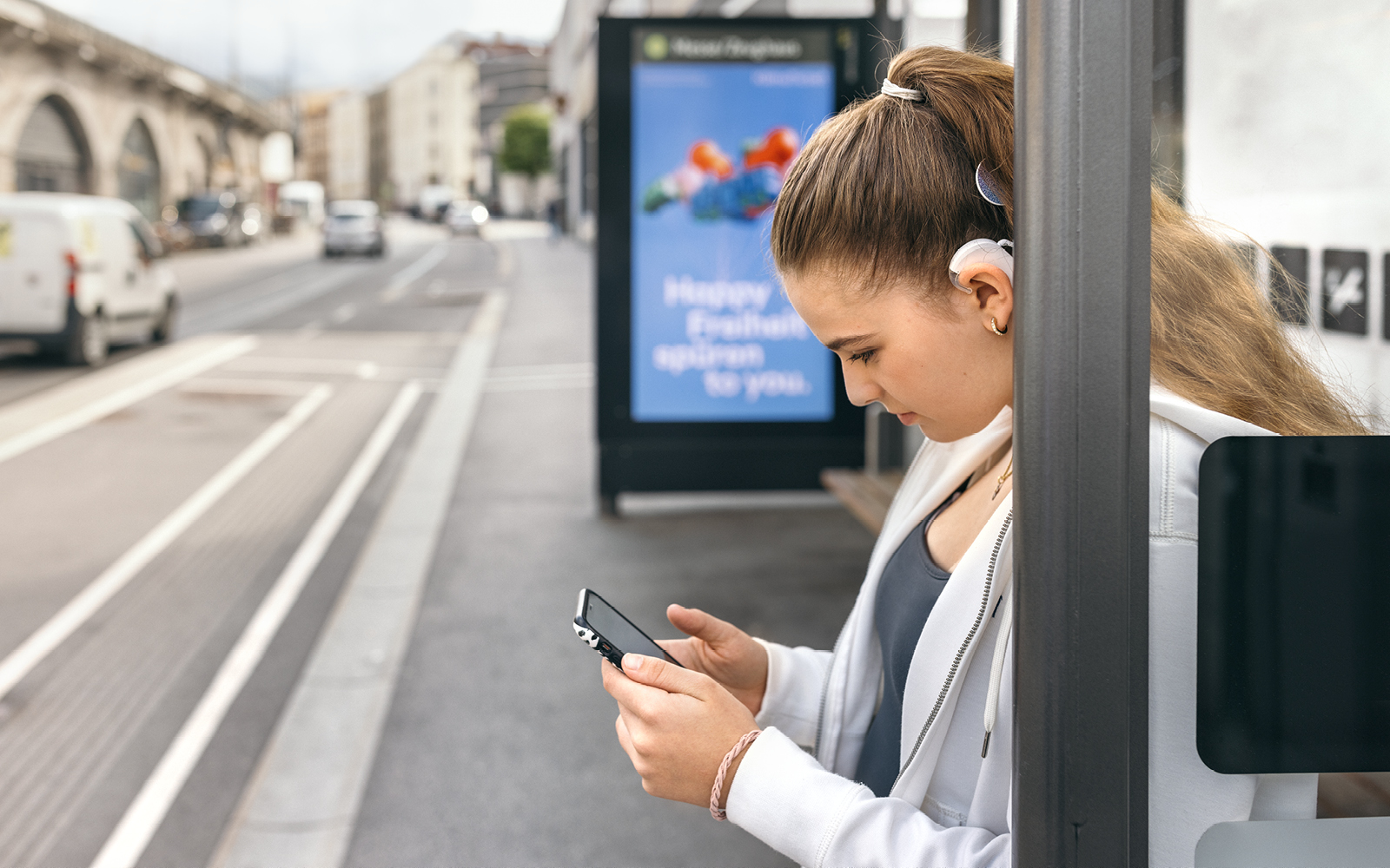 A teenage girl streams music to her SONNET 3 while waiting at a bus stop.