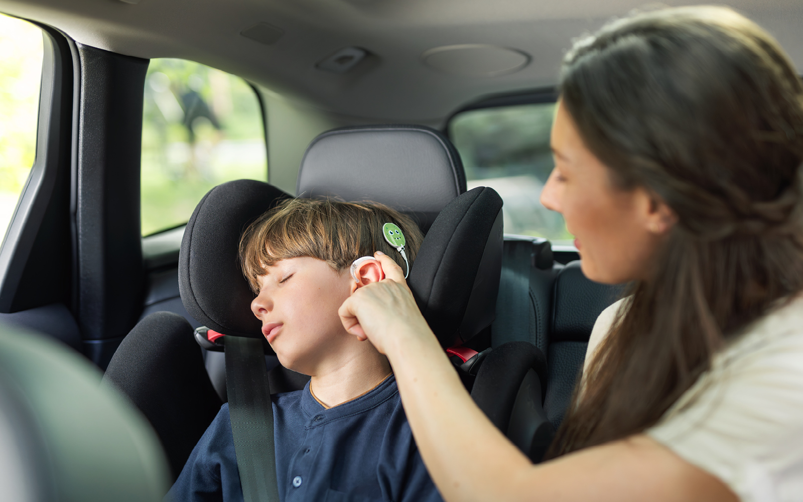 A mother uses SONNET 3's convenient touch key to put her son's audio processor in standby mode so he won't be disturbed while sleeping in the car.