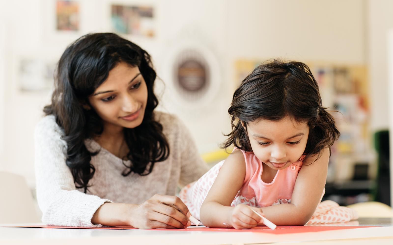 A toddler Who Received a Cochlear Implant Late is painting next to her mother and can Still Benefit From Cochlear Implantation.