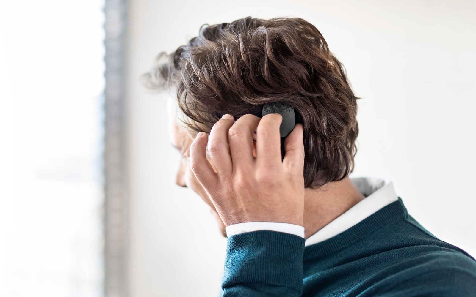 A middle-aged man with unilateral deafness puts on his audio processor in a clinic.