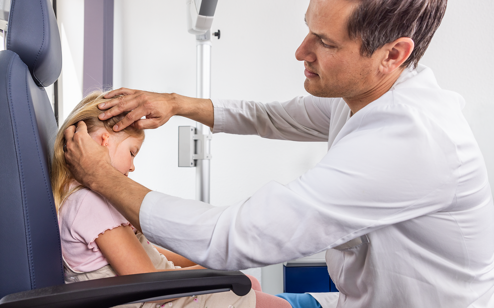 An ENT doctor examines the ear of a young girl with microtia.