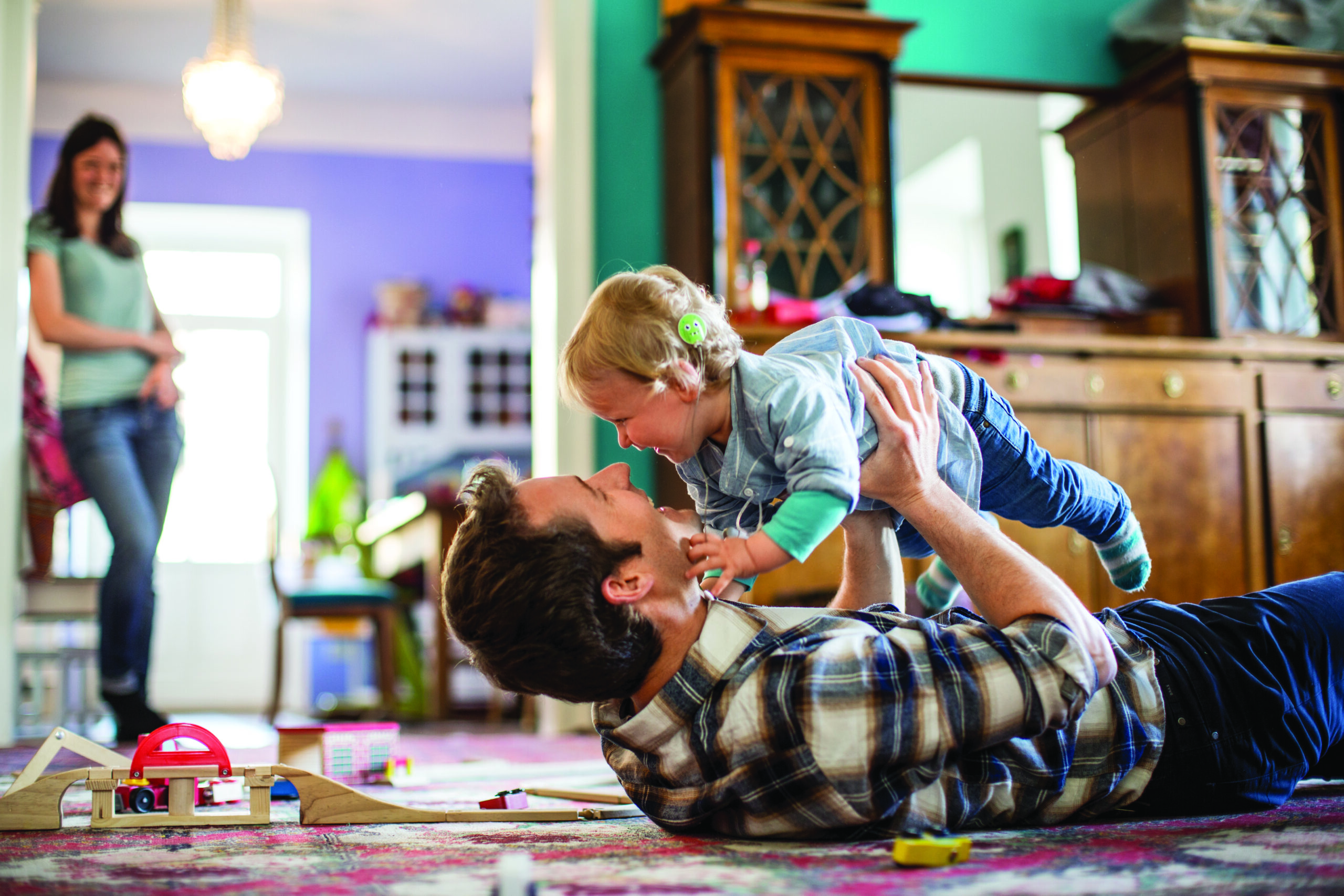 Man holding a child with a woman in the back.