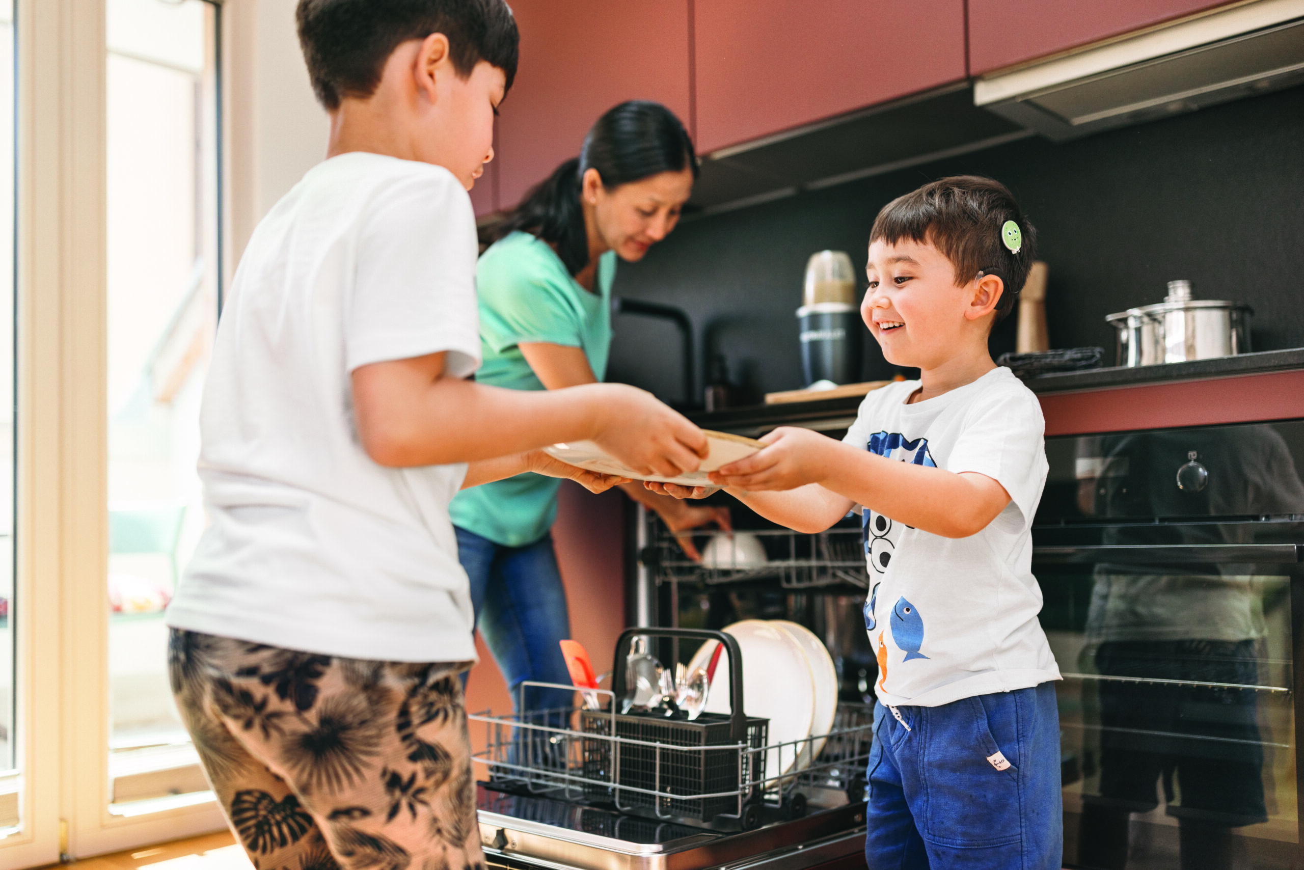 Two children unload a dishwasher with a woman