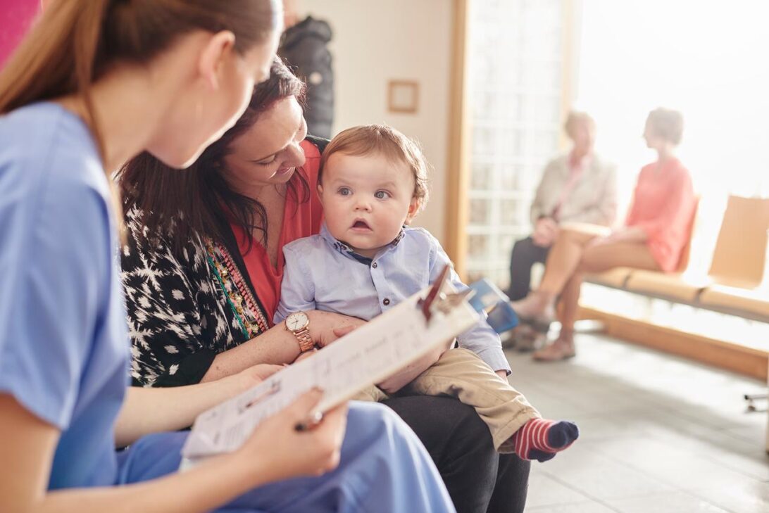 Baby sitting in a waiting room with mother and provider