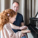Little girl with a cochlear implant playing the piano with her teacher