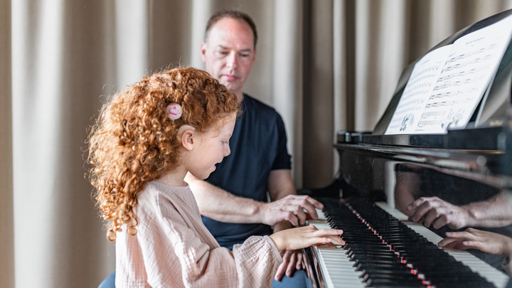 Little girl with a cochlear implant playing the piano with her teacher
