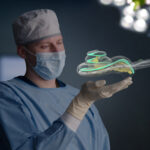 surgeon holding a graphic of a cochlea
