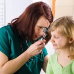 Child having an ear examination with an ENT doctor using an otoscope.