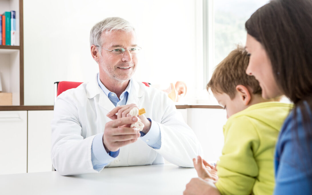 Healthcare professional consulting with a child with SSD and caregiver, demonstrating an ear model.