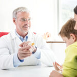 Healthcare professional consulting with a child with SSD and caregiver, demonstrating an ear model.